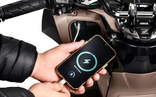 Detalhe da entrada USB-C carregando celular no porta-luvas da PCX